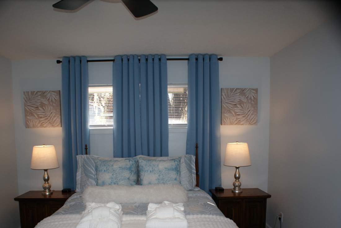 Queen bedroom with blue curtains and bedside lamps